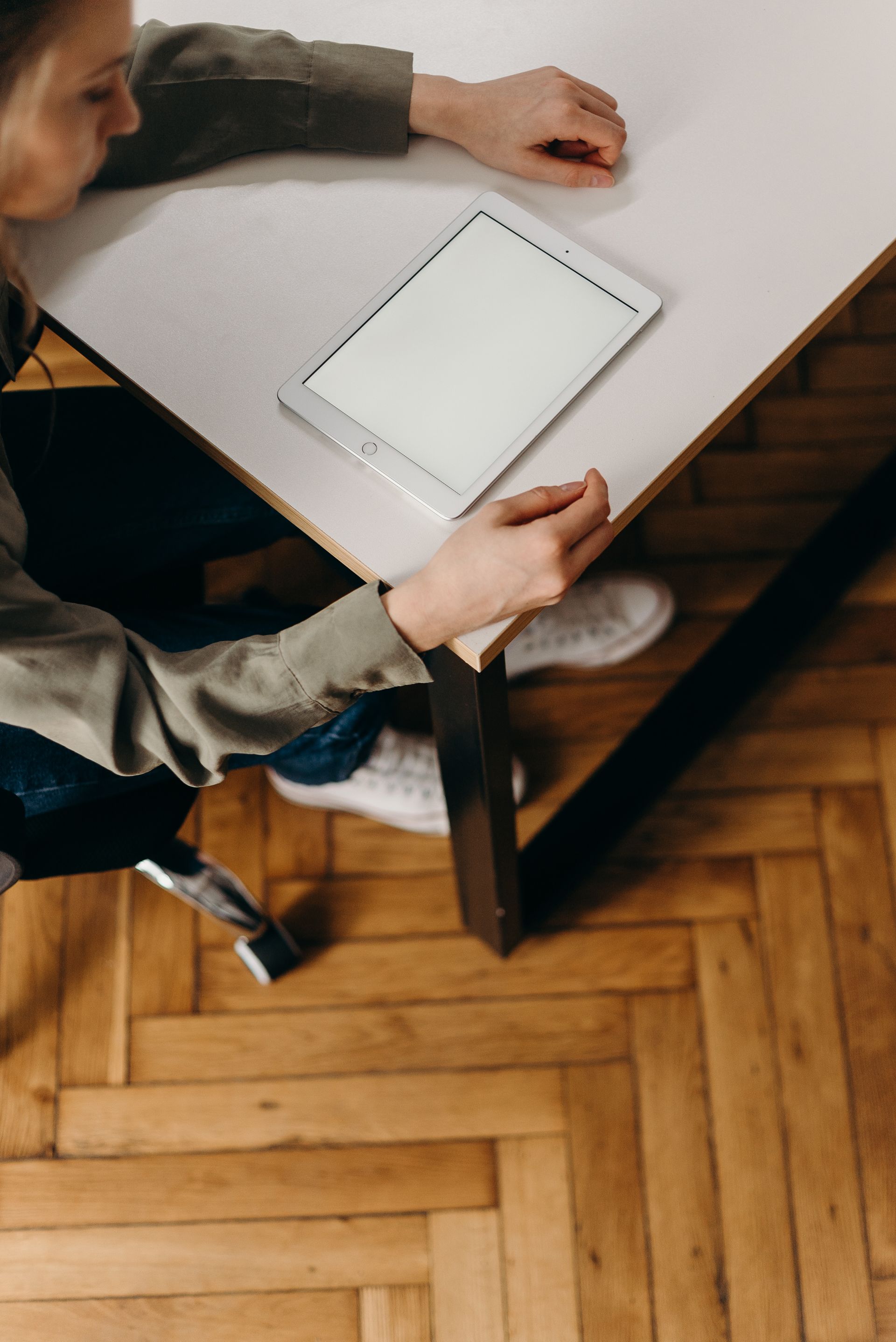 A woman is sitting at a table using a tablet computer.