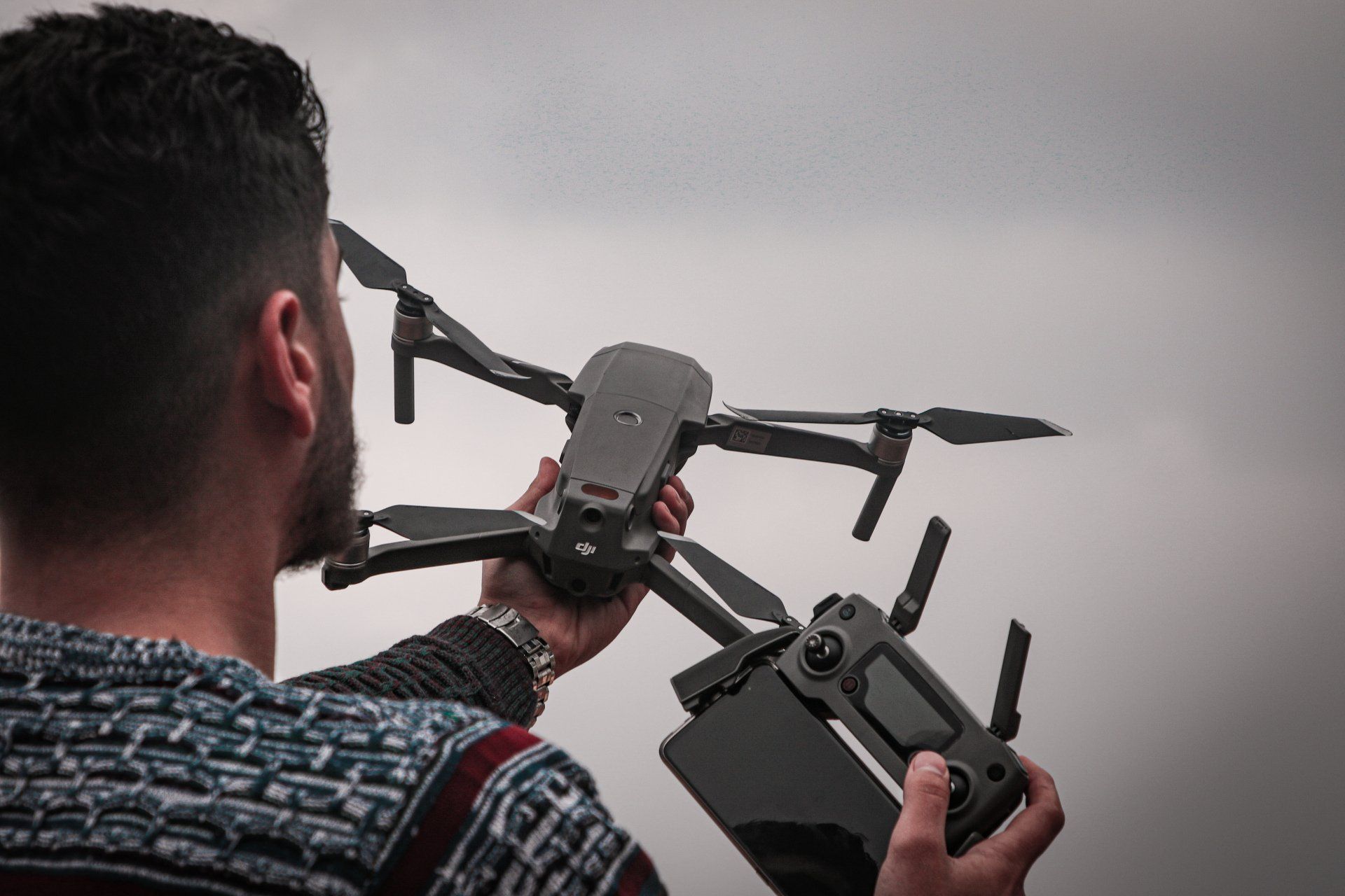 A man is holding a remote control and a drone.