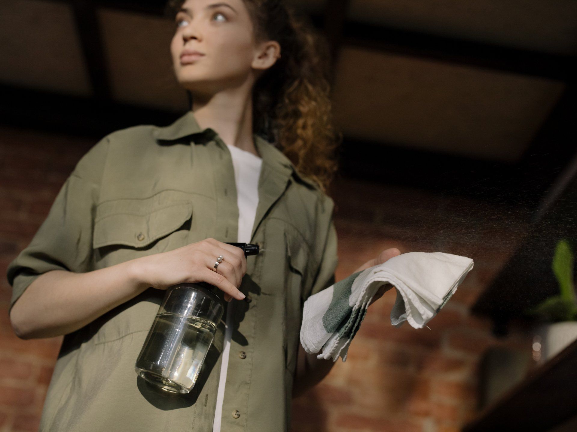 a woman holding a spray bottle and a rag