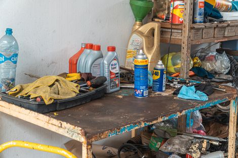 A messy workbench with bottles of oil and spray bottles on it