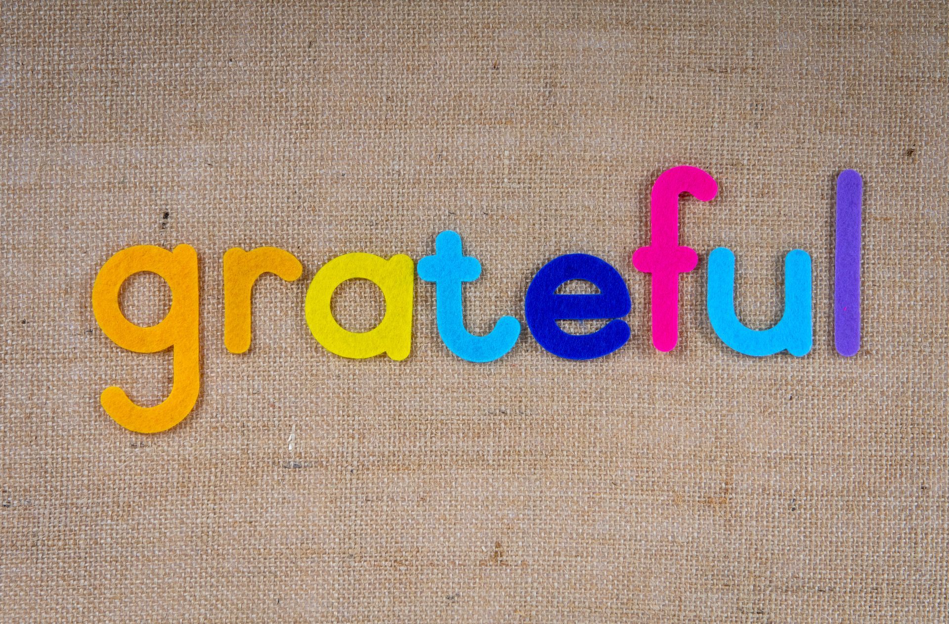 The word grateful is written in colorful letters on a canvas.