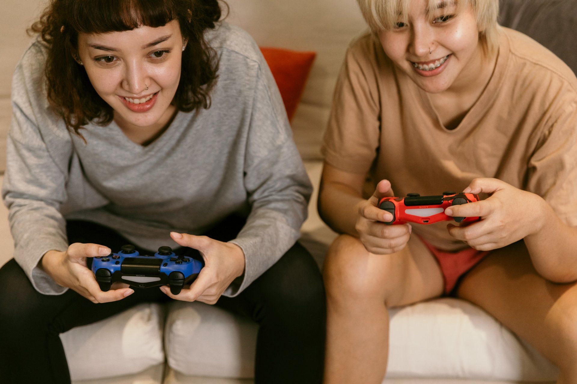 Two women are sitting on a couch playing a video game.