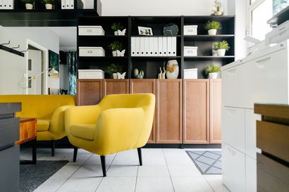 A kitchen with white cabinets , wooden floors , stainless steel appliances and a large island with chairs.