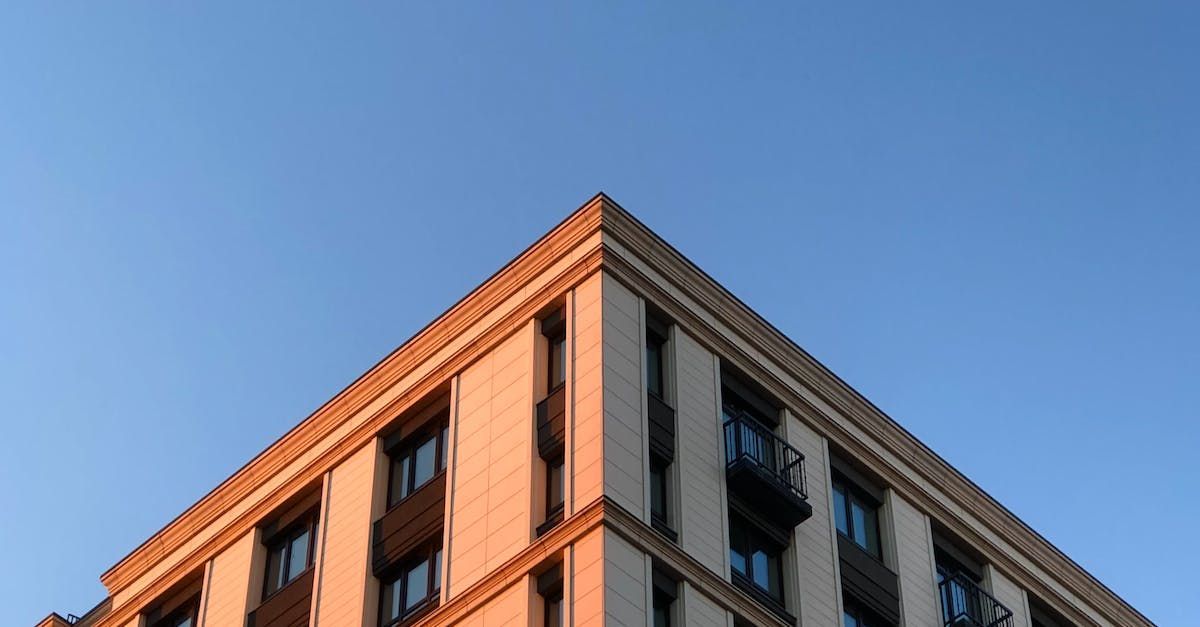 Corner of building against blue sky, lit by golden sunlight.