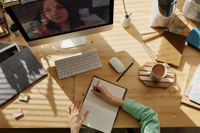 A person is sitting at a desk with a computer and a notebook.