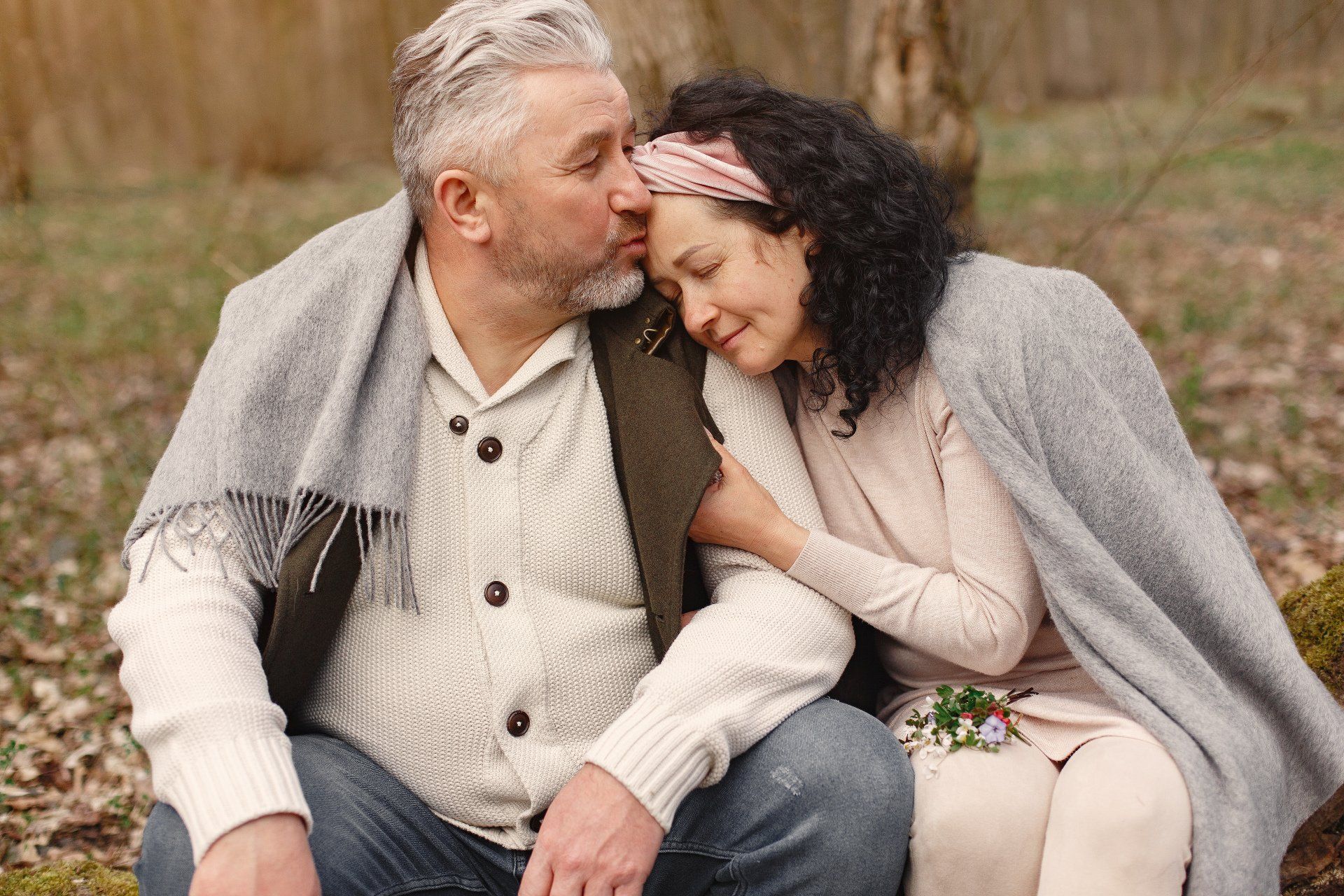 a man and a woman are sitting on a rock in the woods .