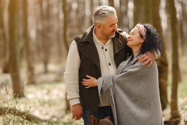 A man and a woman are hugging each other in the woods.