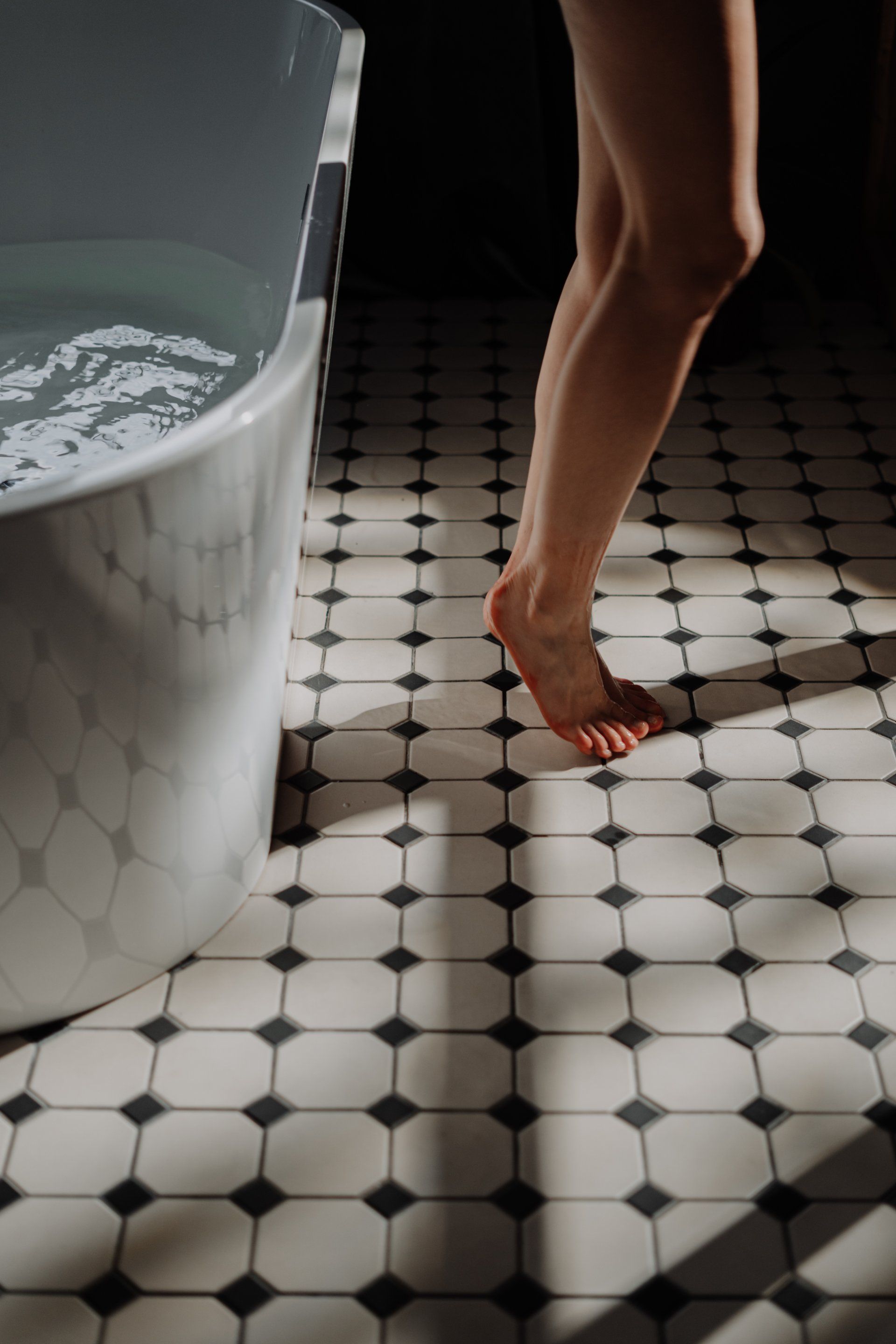 Une femme se tient pieds nus dans une baignoire.
