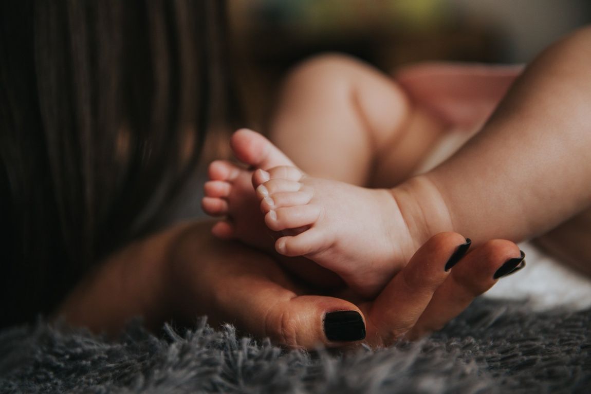 a woman is holding a baby 's foot in her hands .