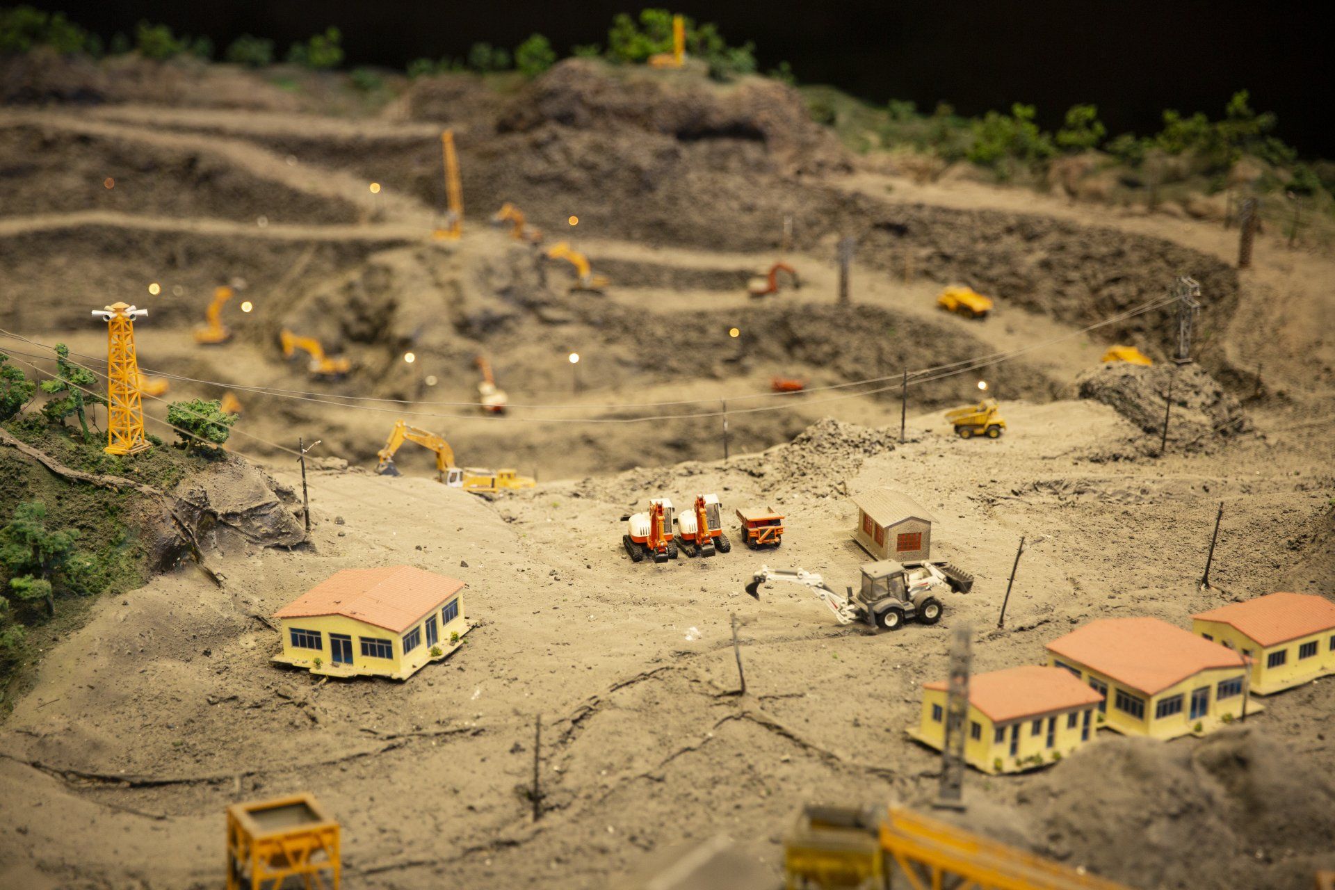Diorama miniature de chantier de construction avec excavatrices, chemins de terre et petits bâtiments dans un paysage poussiéreux
