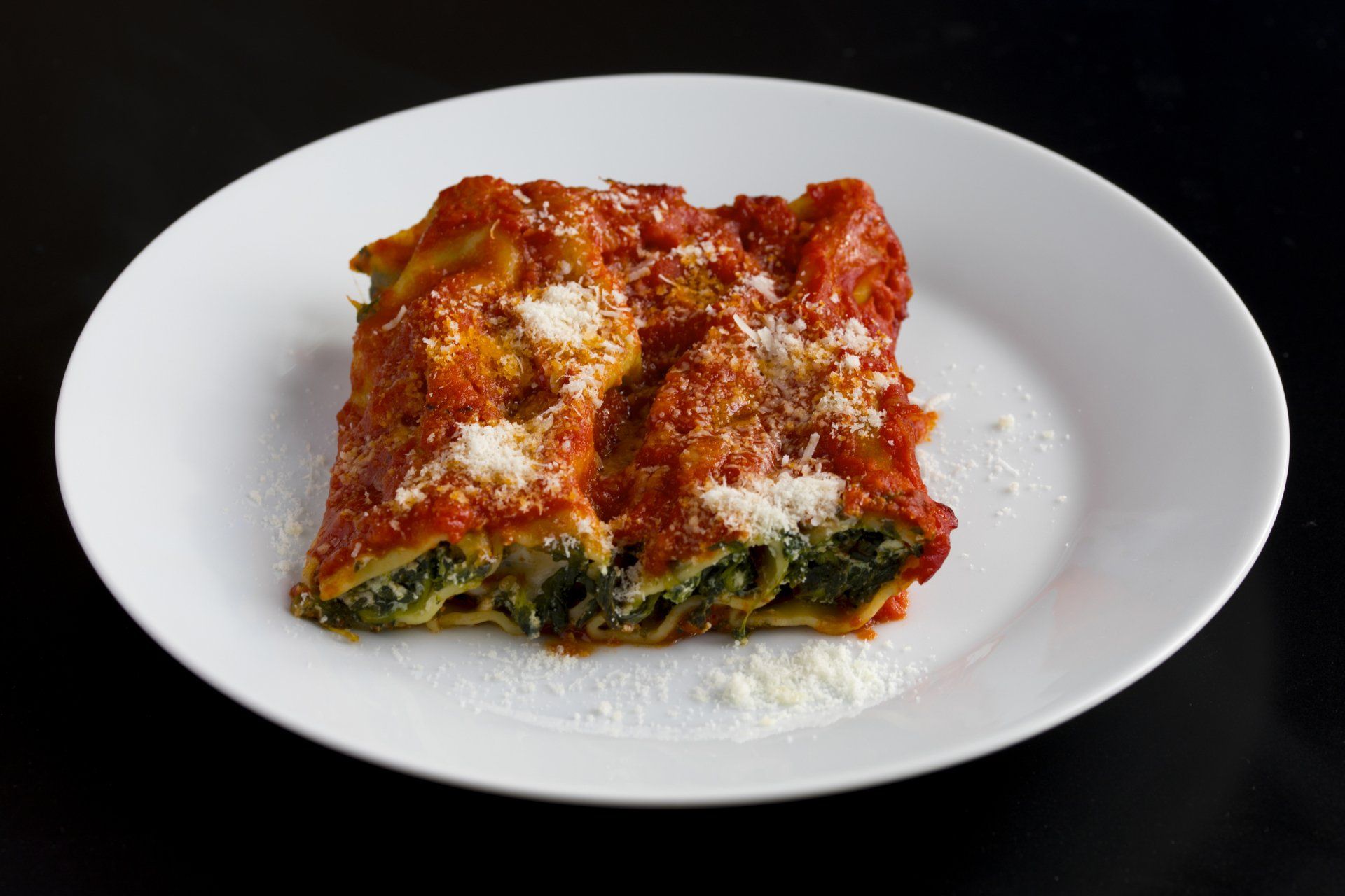 A white plate topped with a slice of lasagna