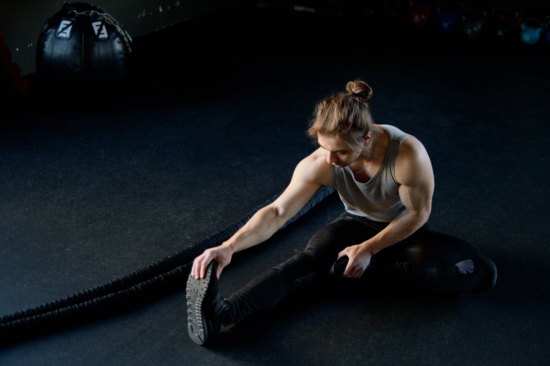 A man is sitting on the floor stretching his legs.