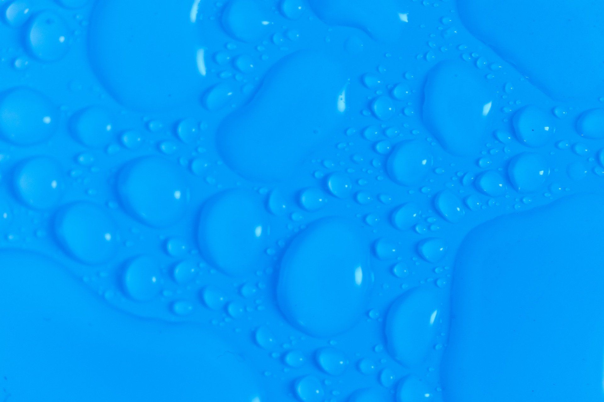 A close up of water drops on a blue surface.