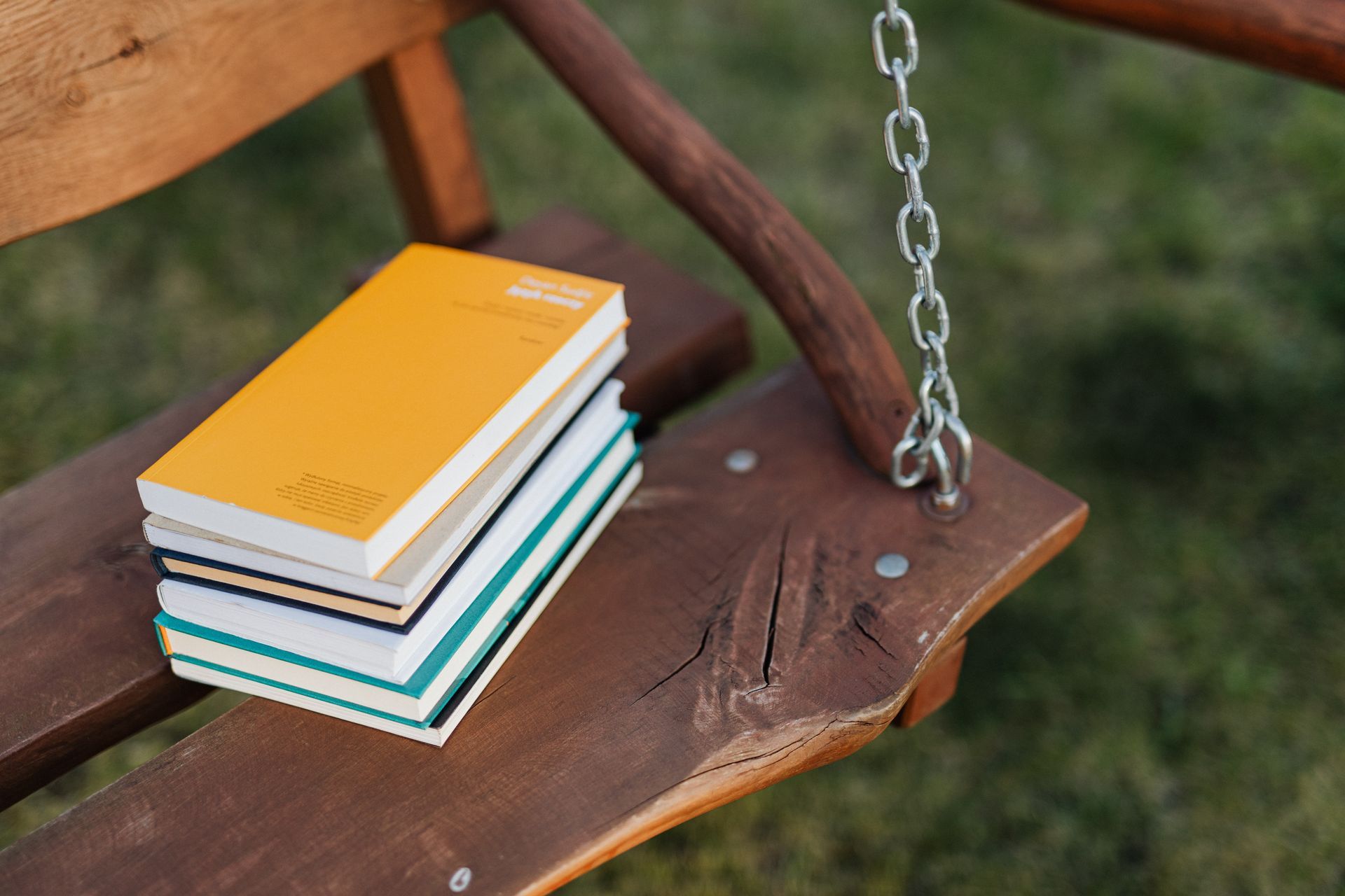 a stack of books is sitting on a wooden bench .