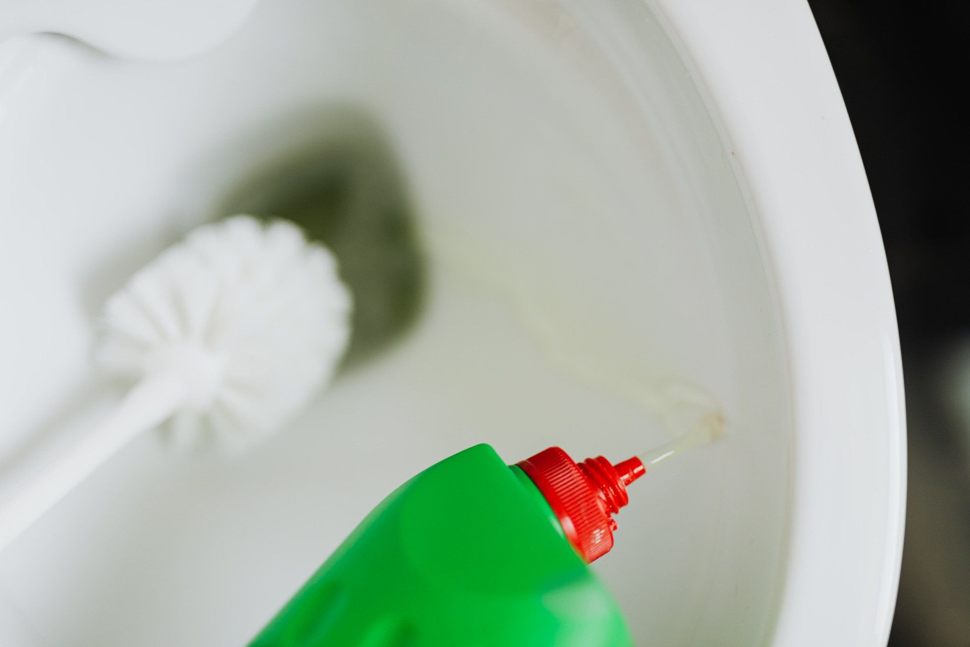 Bathroom toilet being scrubbed with green cleaning solutions