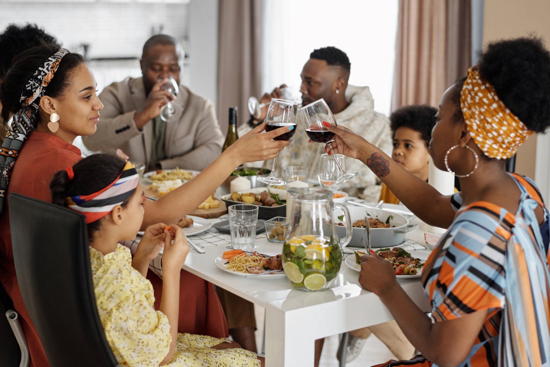 A family is sitting at a table toasting with wine glasses.