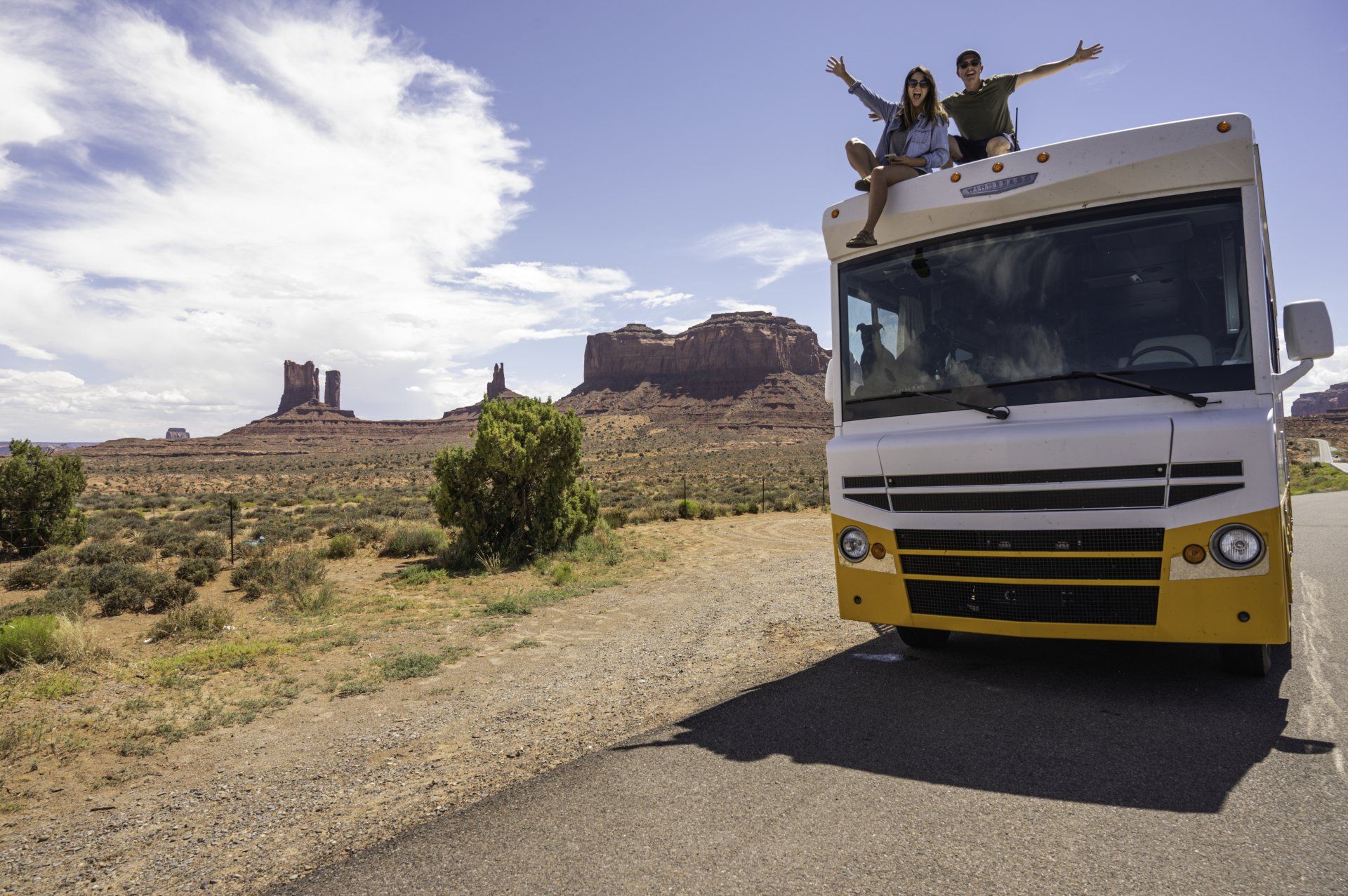 A man and a woman are sitting on top of a rv.