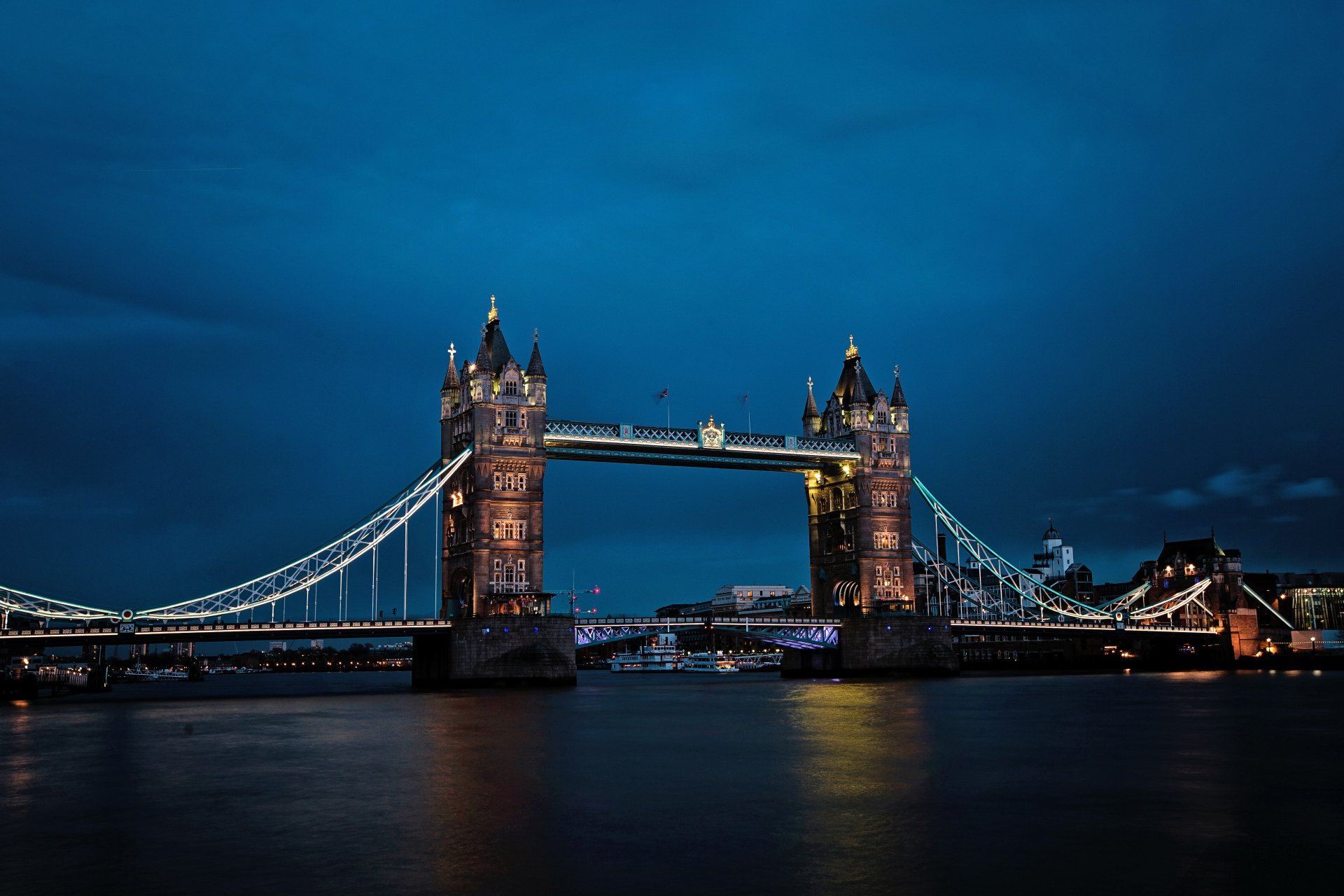 The tower bridge in london is lit up at night.