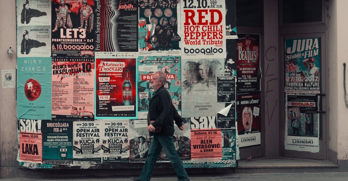 A man is walking past a wall covered in posters.