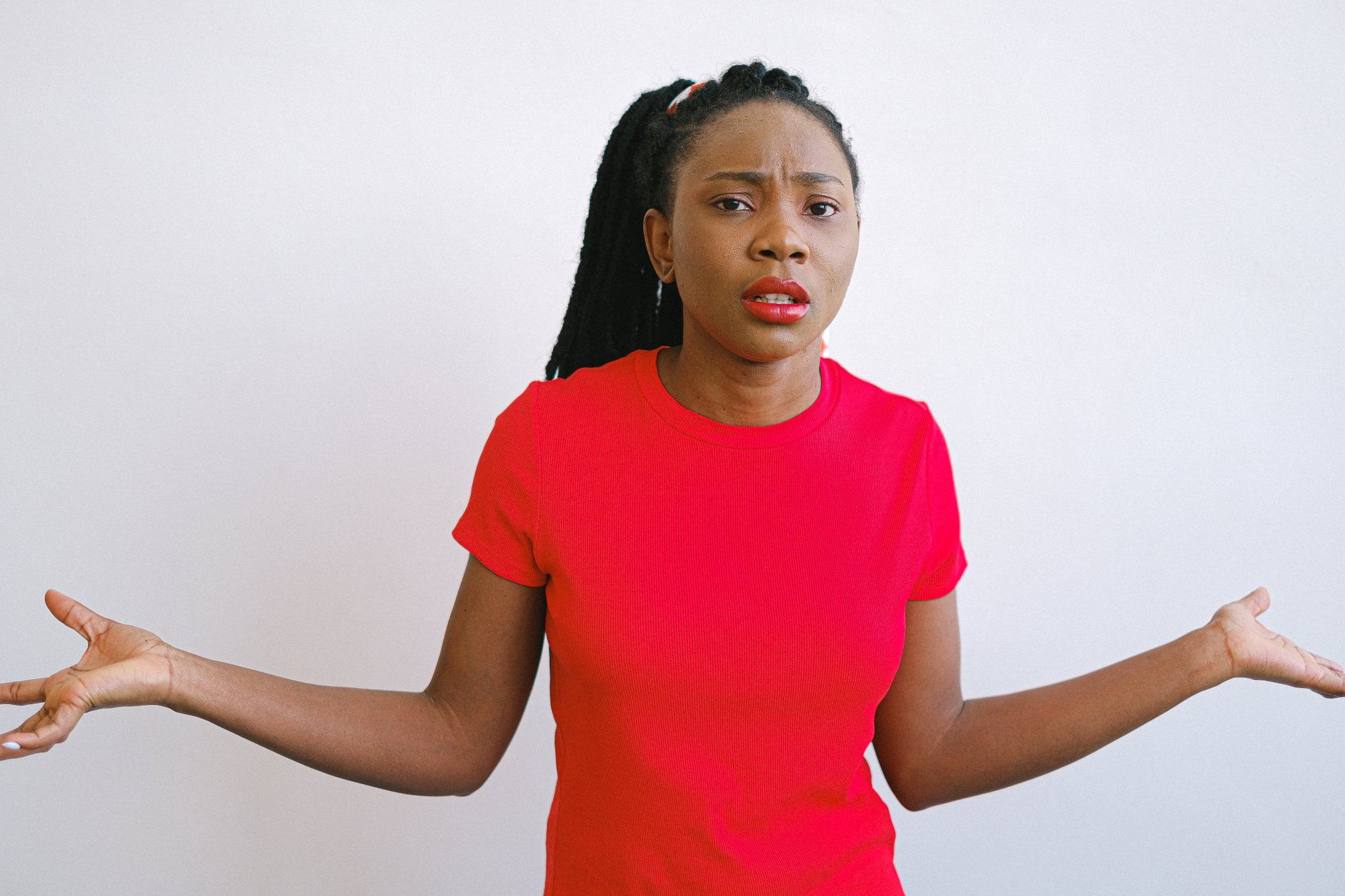 a woman in a red shirt is shrugging her shoulders 