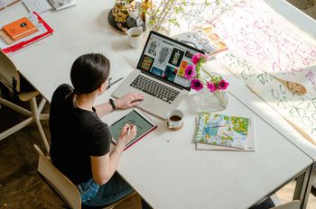 A woman is sitting at a table using a laptop computer.