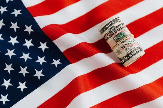 A roll of money is sitting on top of an american flag.