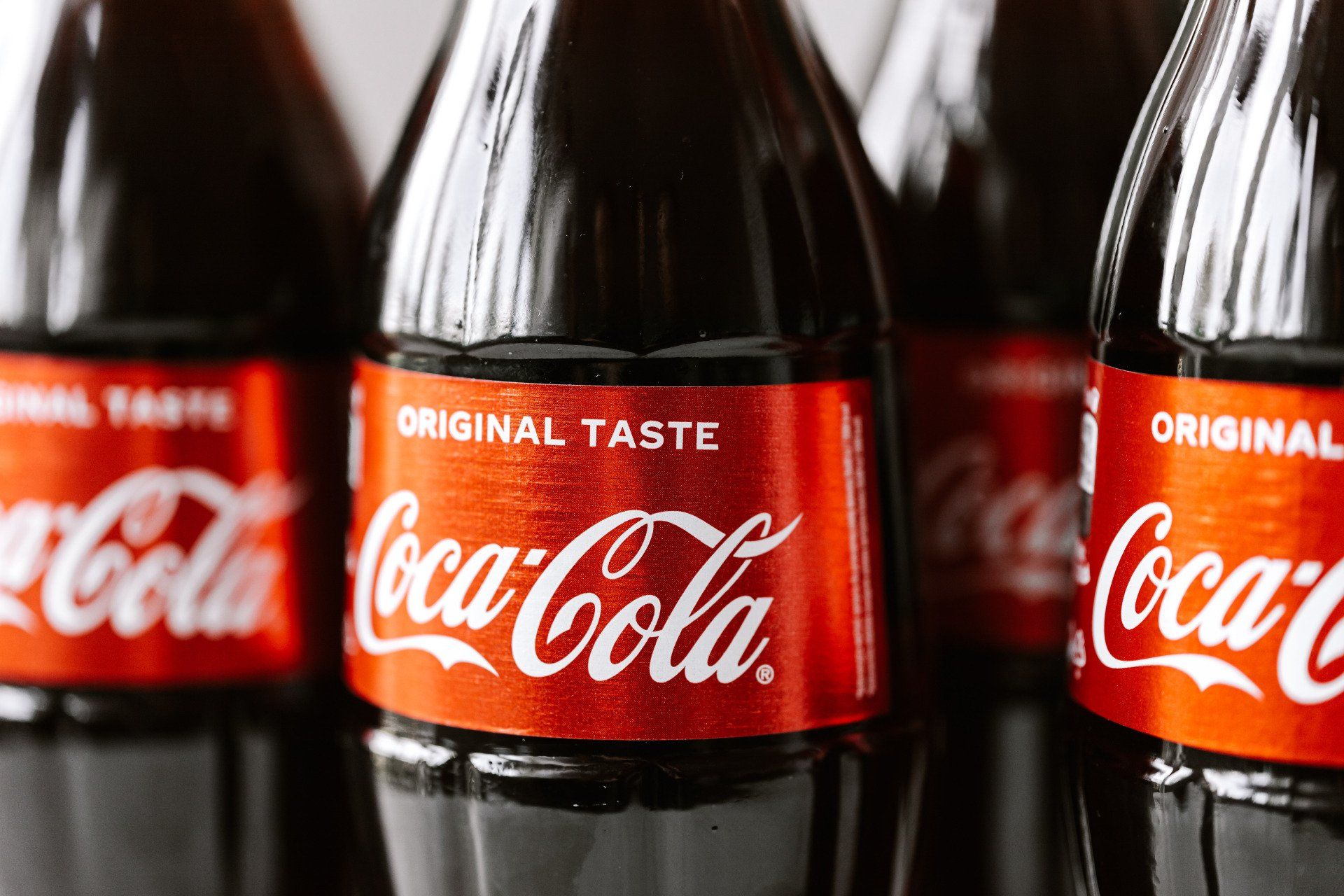 A row of coca cola bottles are lined up on a table.