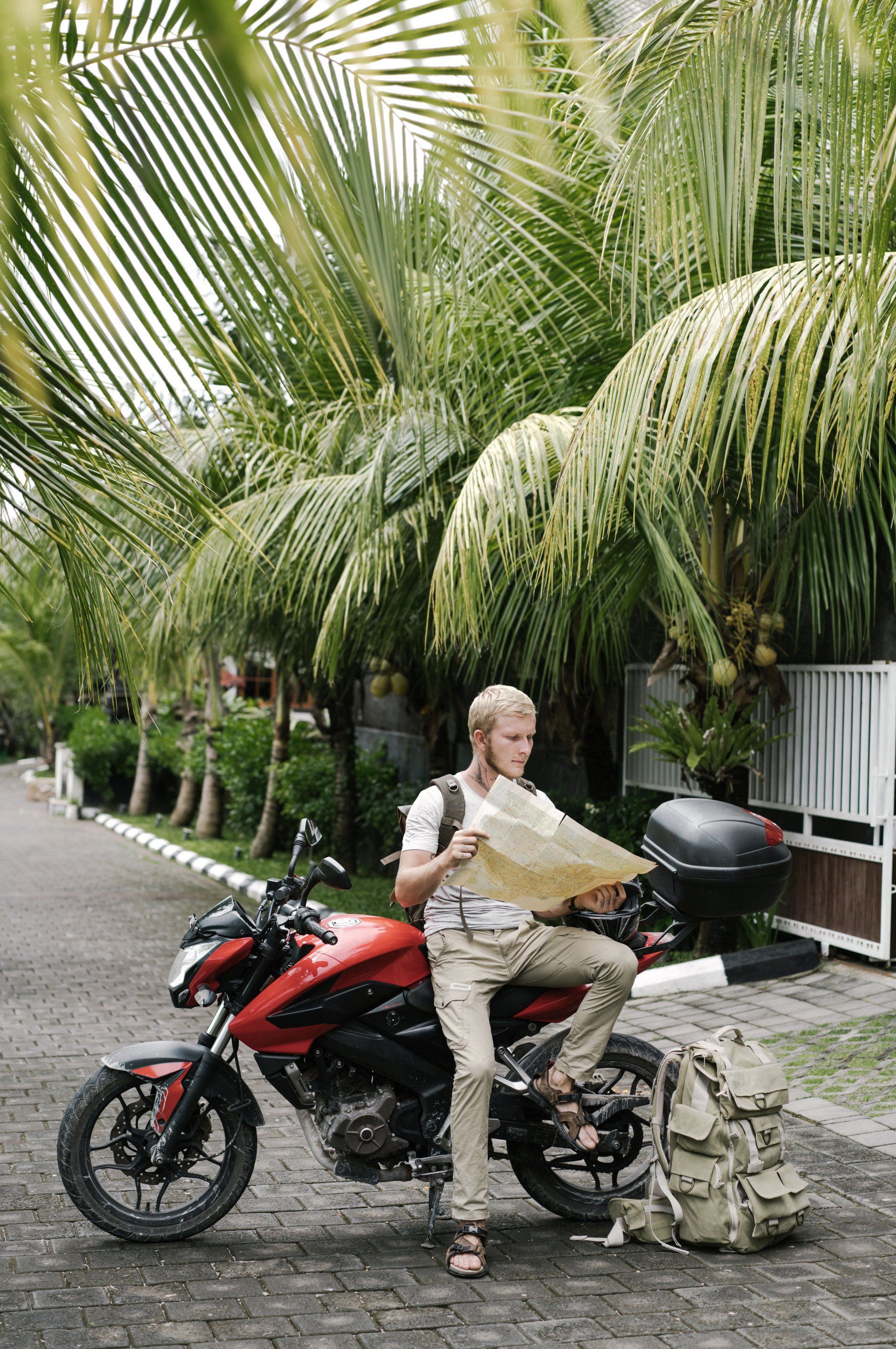 A man is sitting on a motorcycle looking at a map.