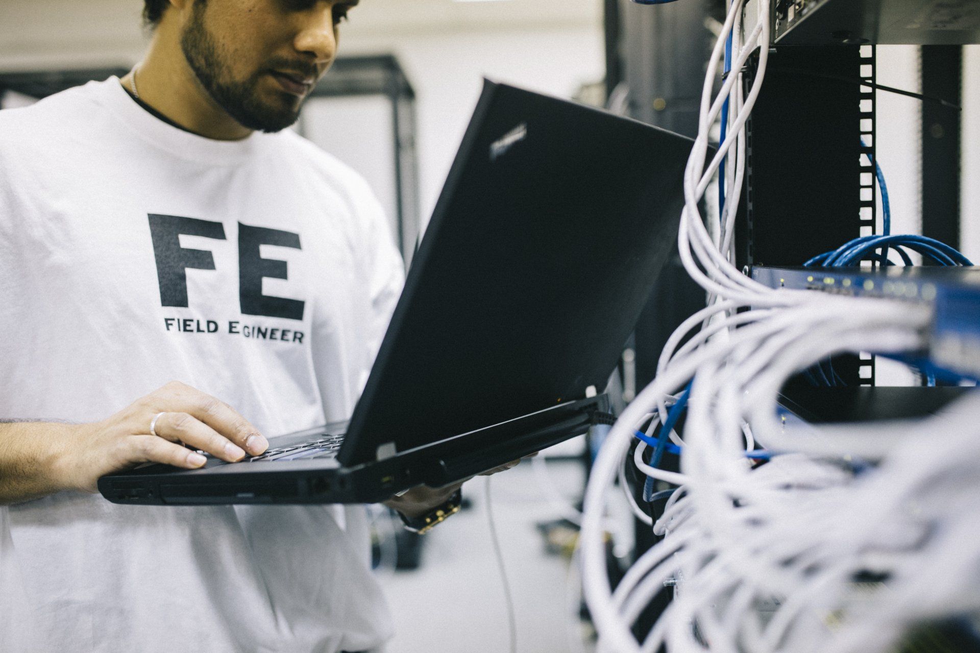 a man wearing a white shirt that says fe is using a laptop