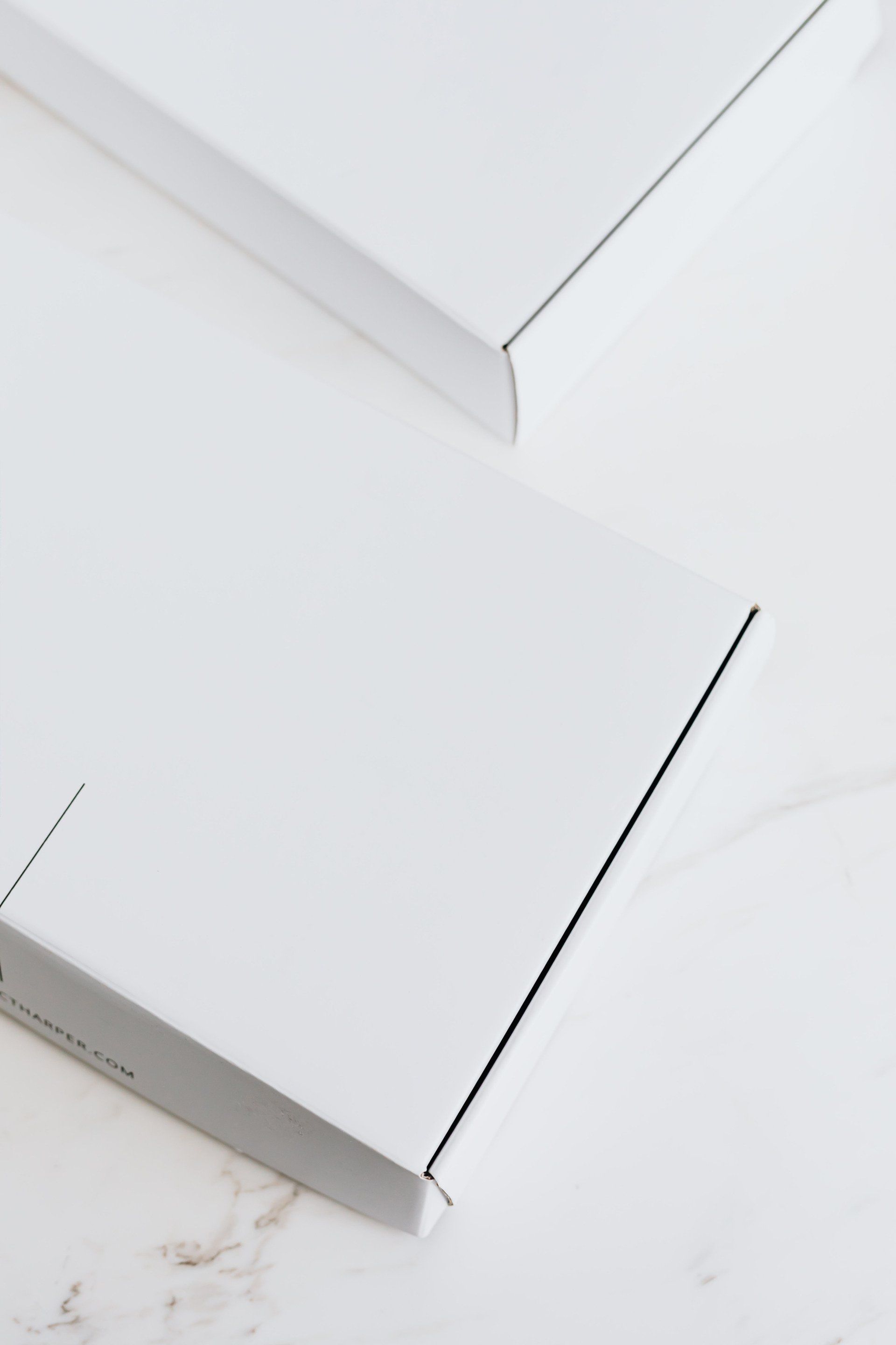 Duas caixas brancas estão empilhadas uma sobre a outra sobre uma mesa.