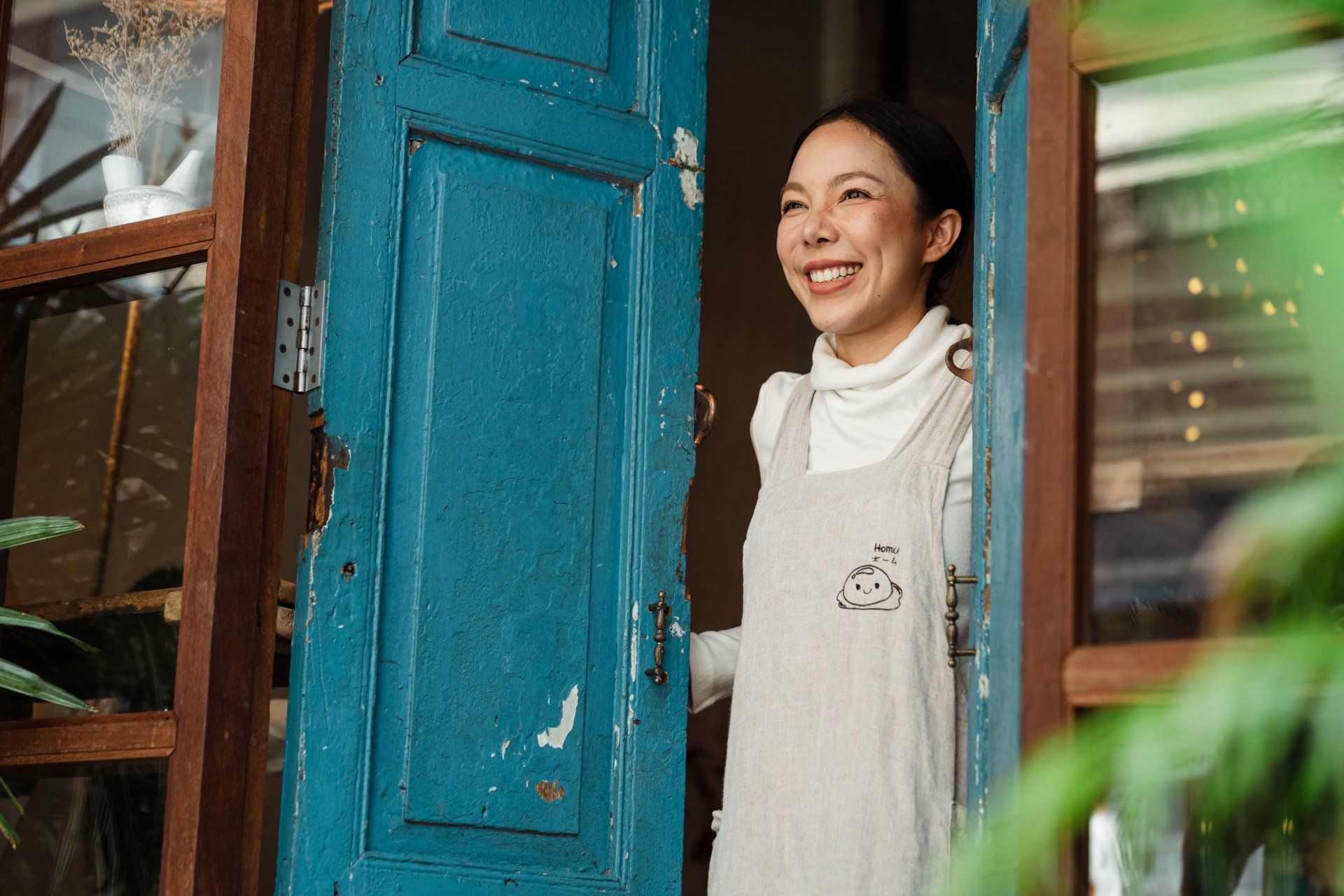 A woman is smiling while standing in front of a blue door.