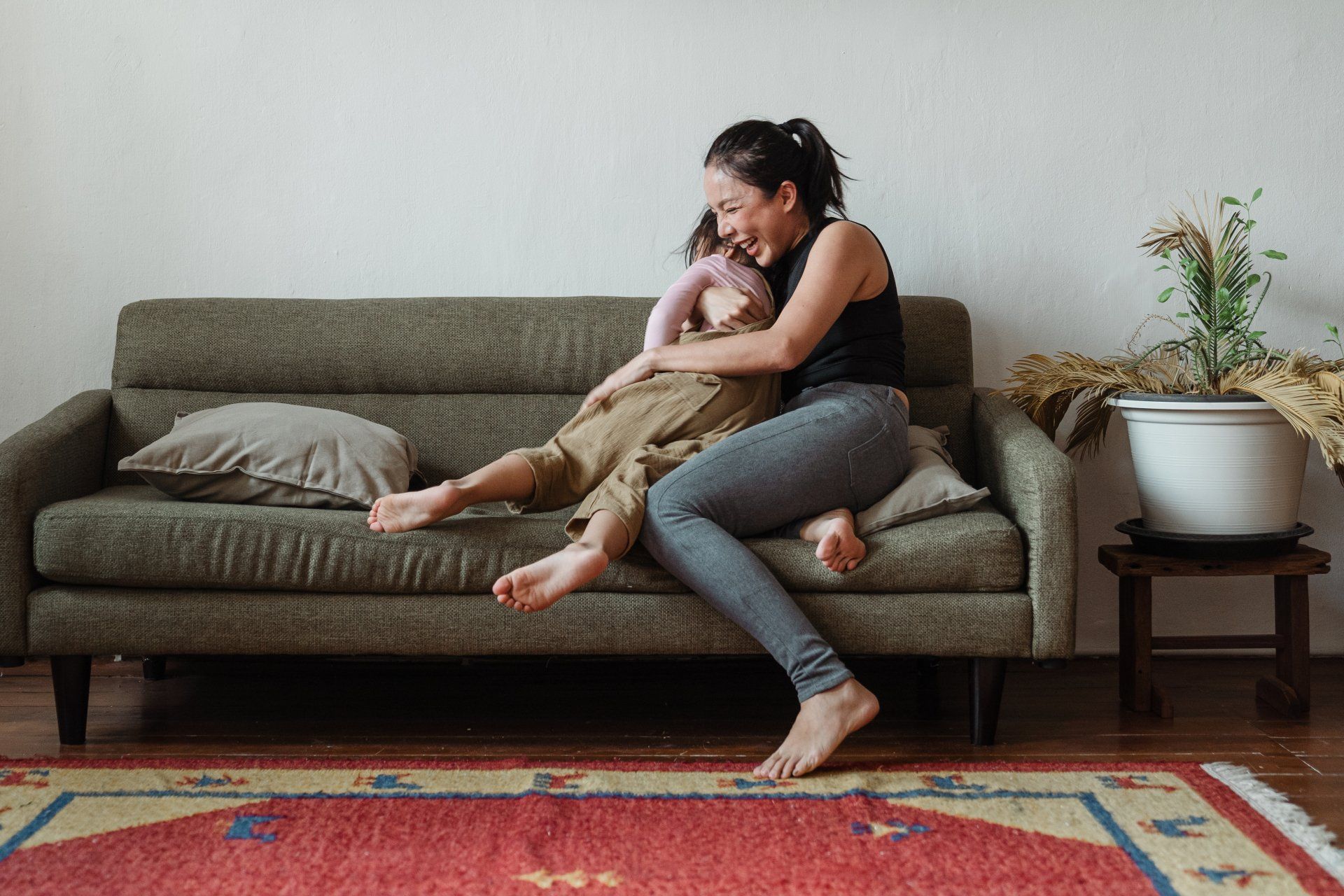 A woman is sitting on a couch holding a child.