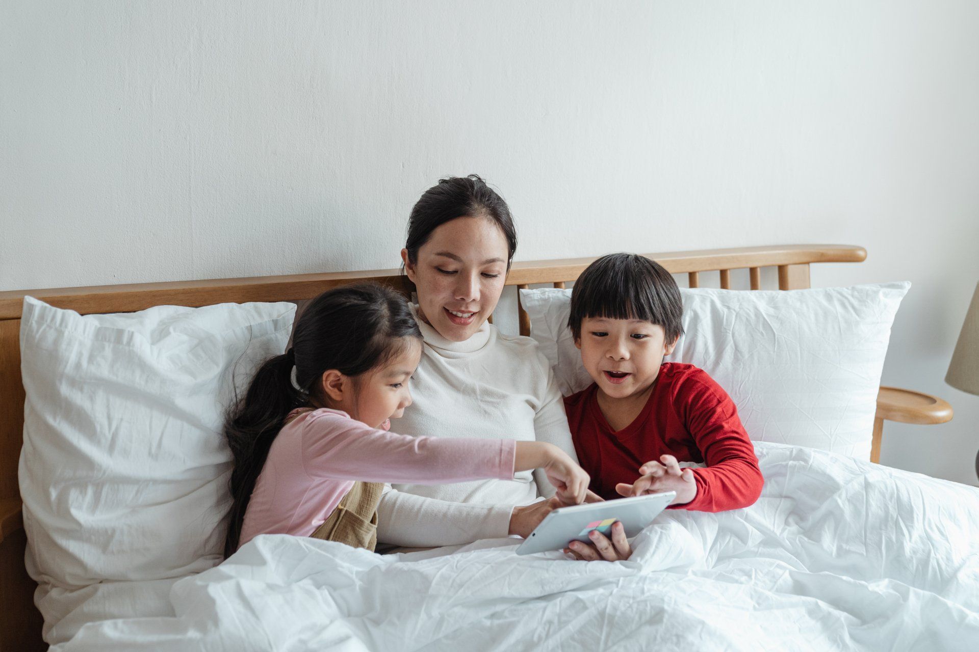 Mother and two young children cuddled up using a touchscreen media device together