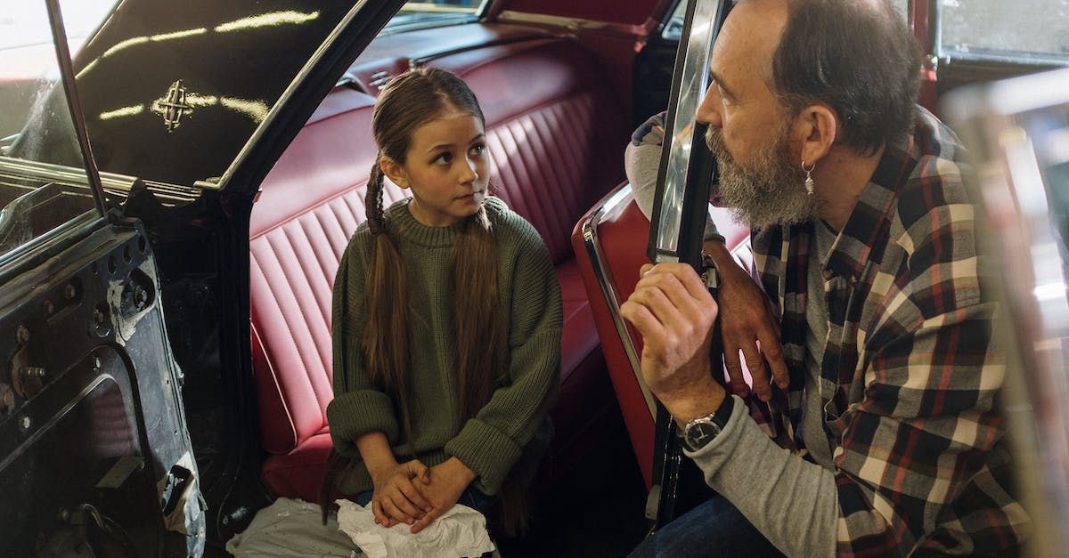 a man and a little girl are sitting in the back seat of a car .