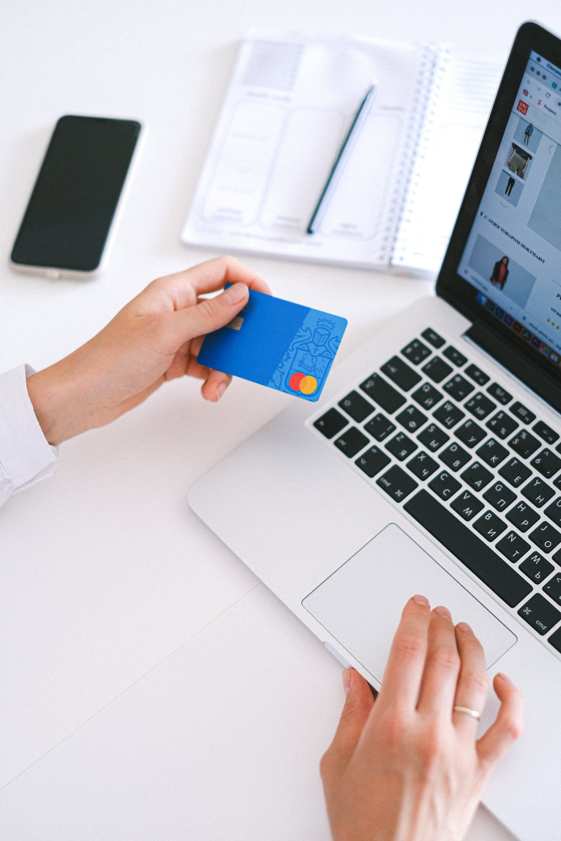 a person is holding a credit card in front of a laptop computer .