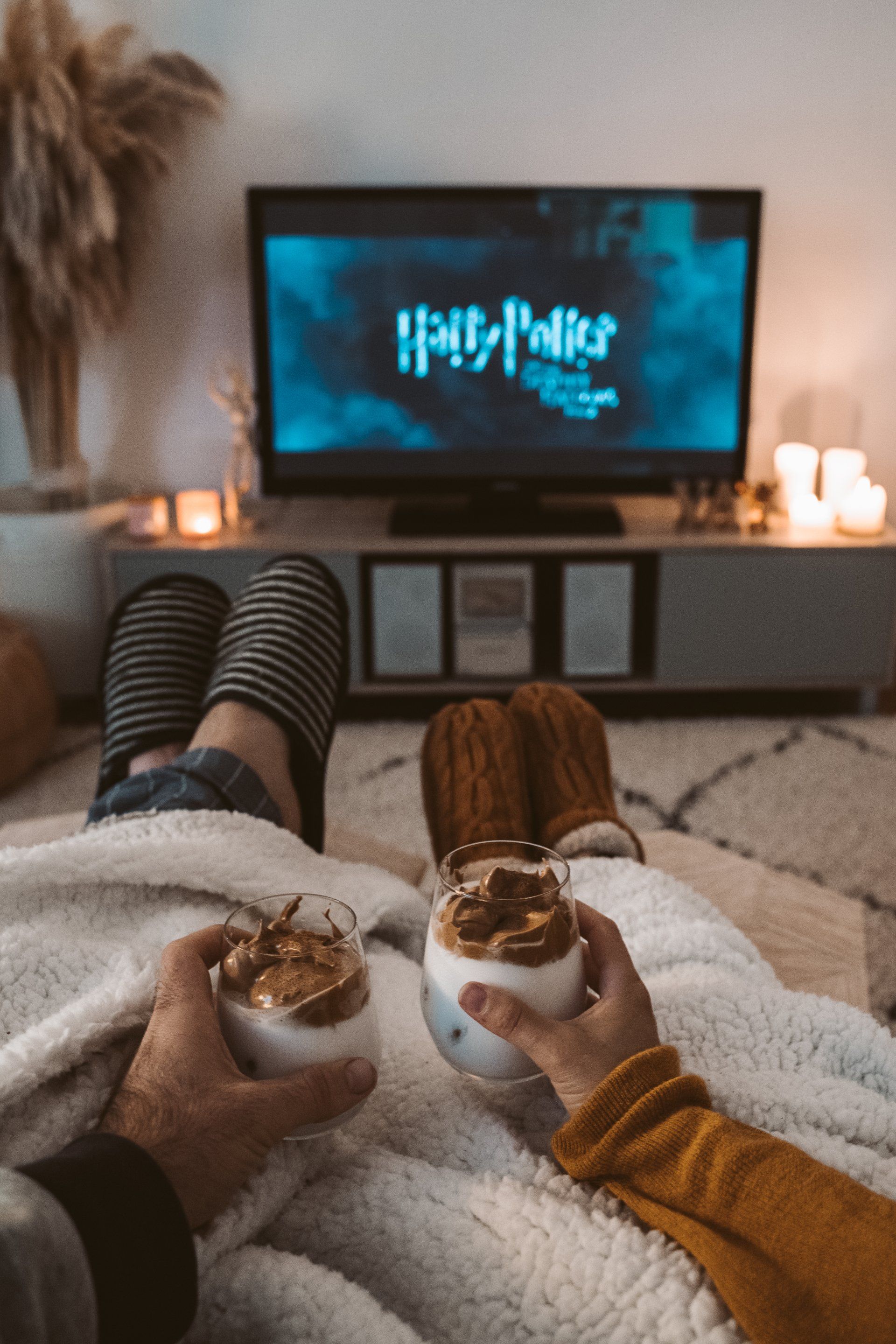 a couple is sitting on a couch watching a harry potter movie .