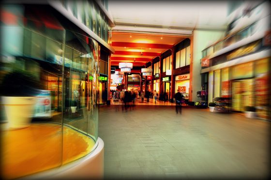 A blurry picture of a shopping mall with people walking through it.