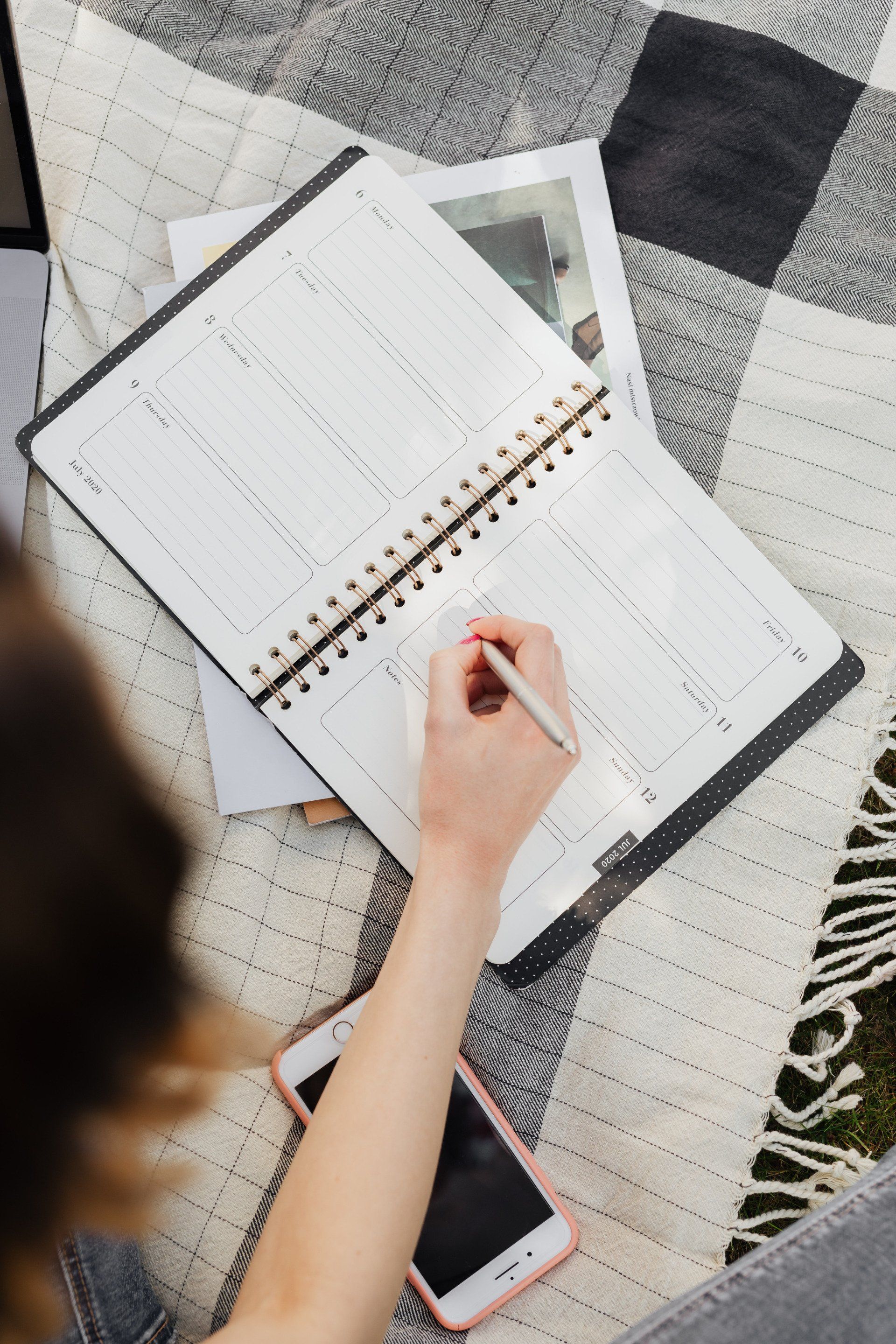 A woman is sitting on a couch writing in a notebook.