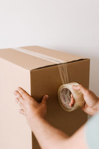 A person is taping a cardboard box with tape.