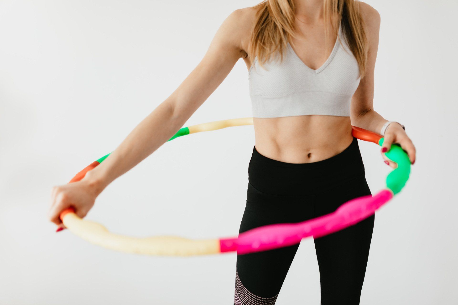A woman is holding a colorful hula hoop in her hands.