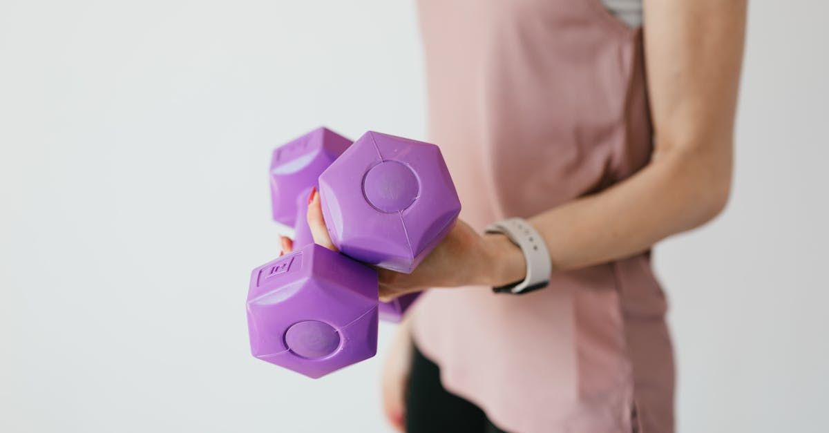 A woman is holding two purple dumbbells in her hands.