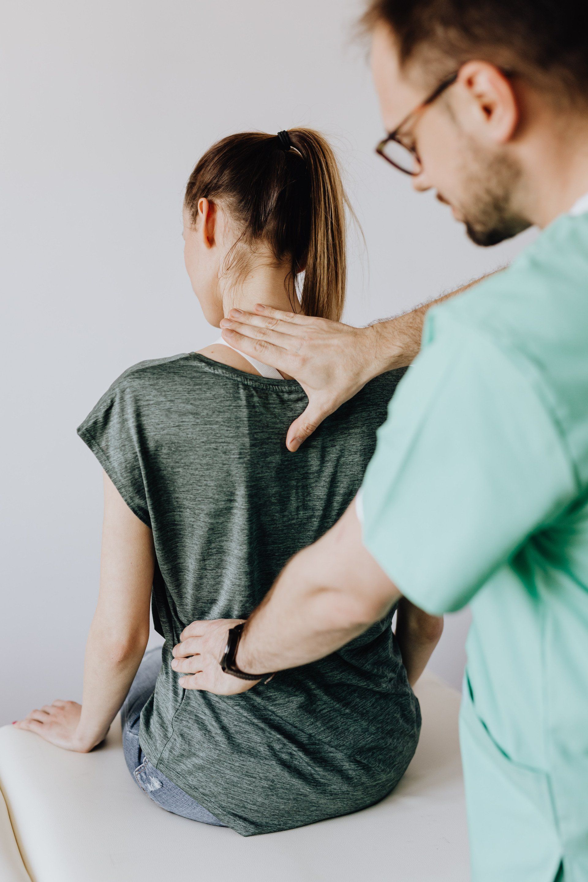 Chiropractor gently examining female patient's back