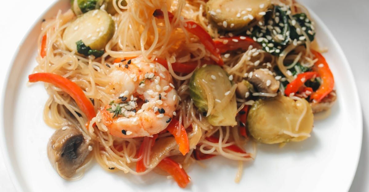 A white plate topped with noodles , shrimp and vegetables.