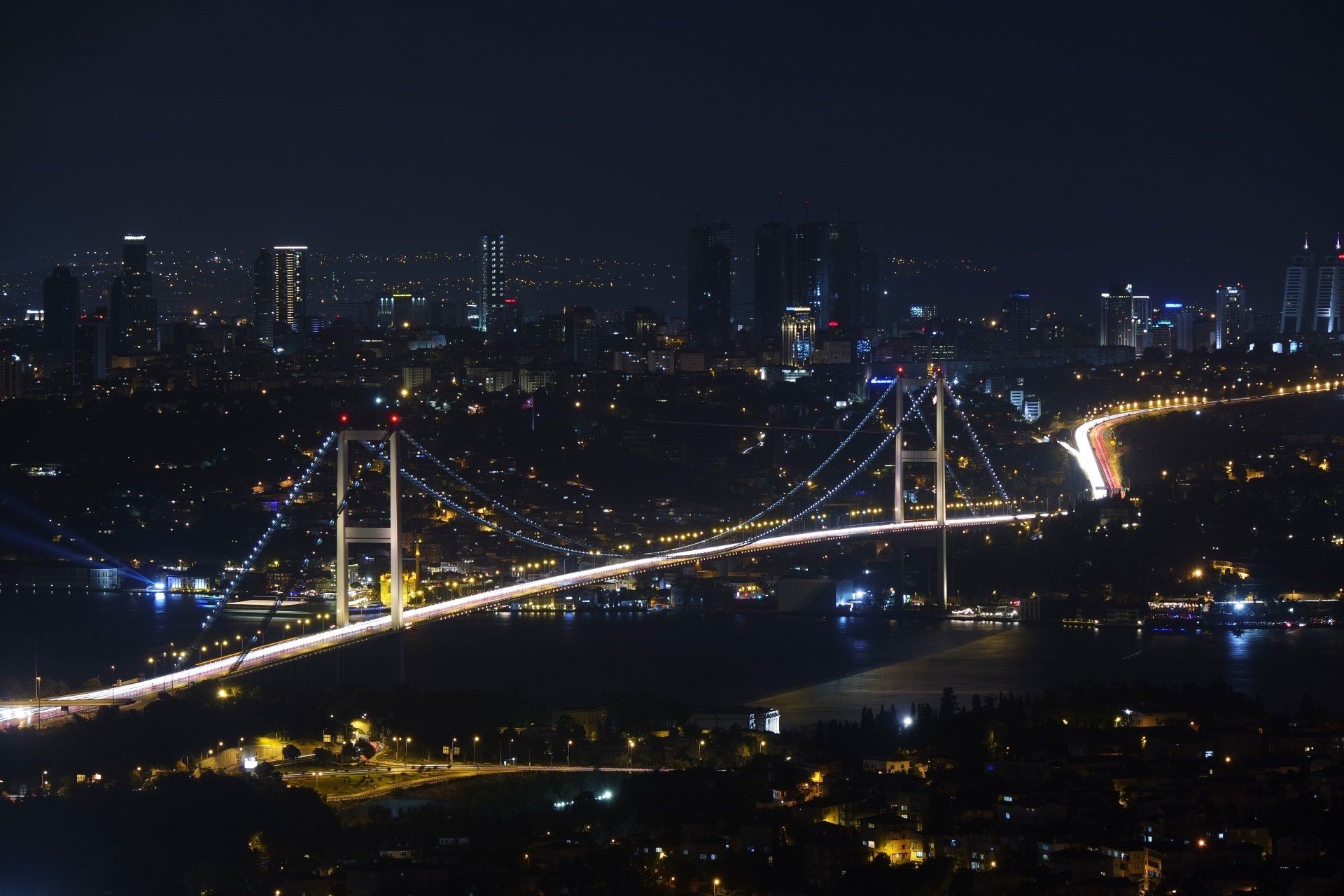 A bridge over a body of water at night with a city in the background