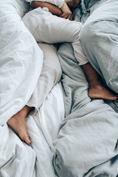 Eine Gruppe von Menschen liegt auf einem Bett mit weißen Laken.