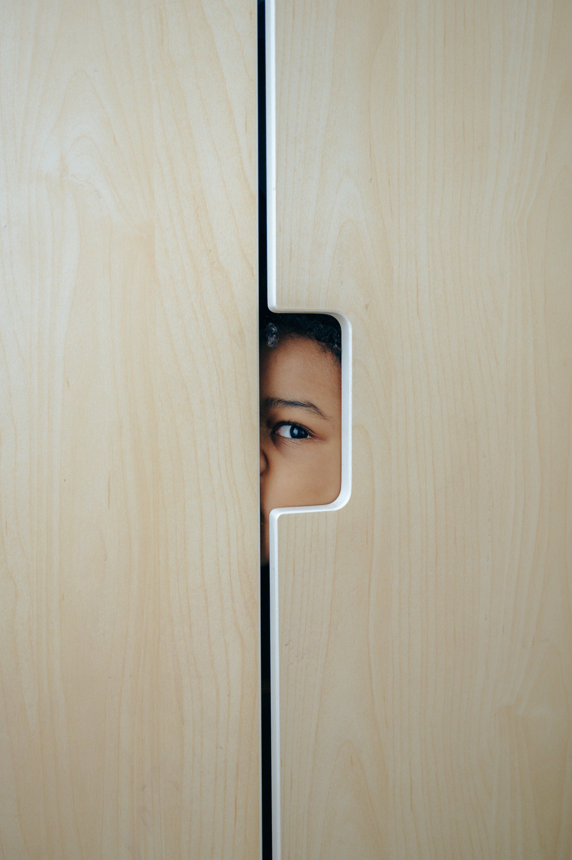 Profile of a person's face looking through a gap in a door