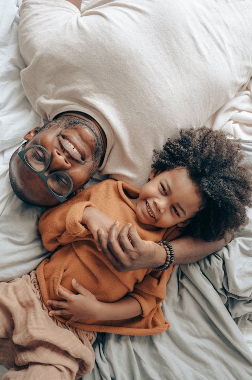 A man and a child are laying on a bed.