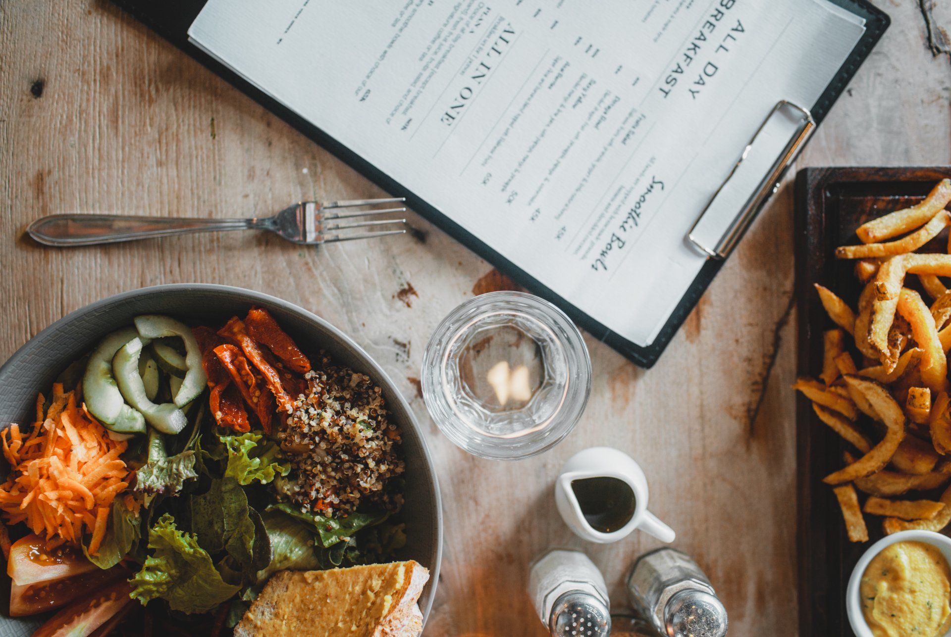 a wooden table topped with a bowl of food and a menu.
