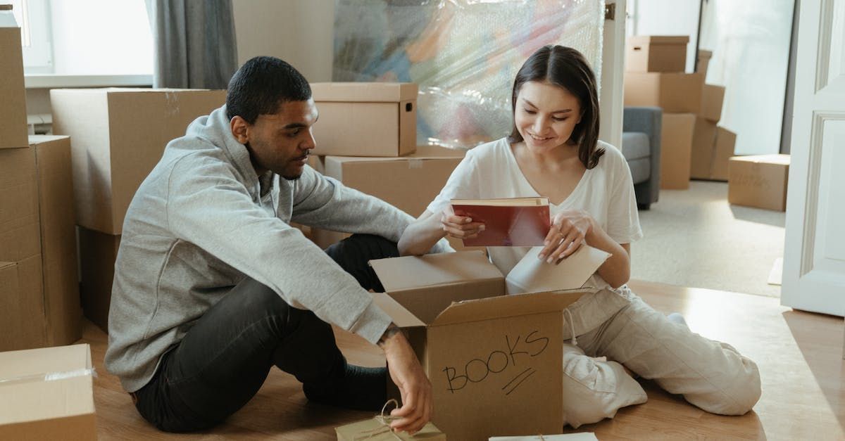 A man and a woman are sitting on the floor looking at a box.
