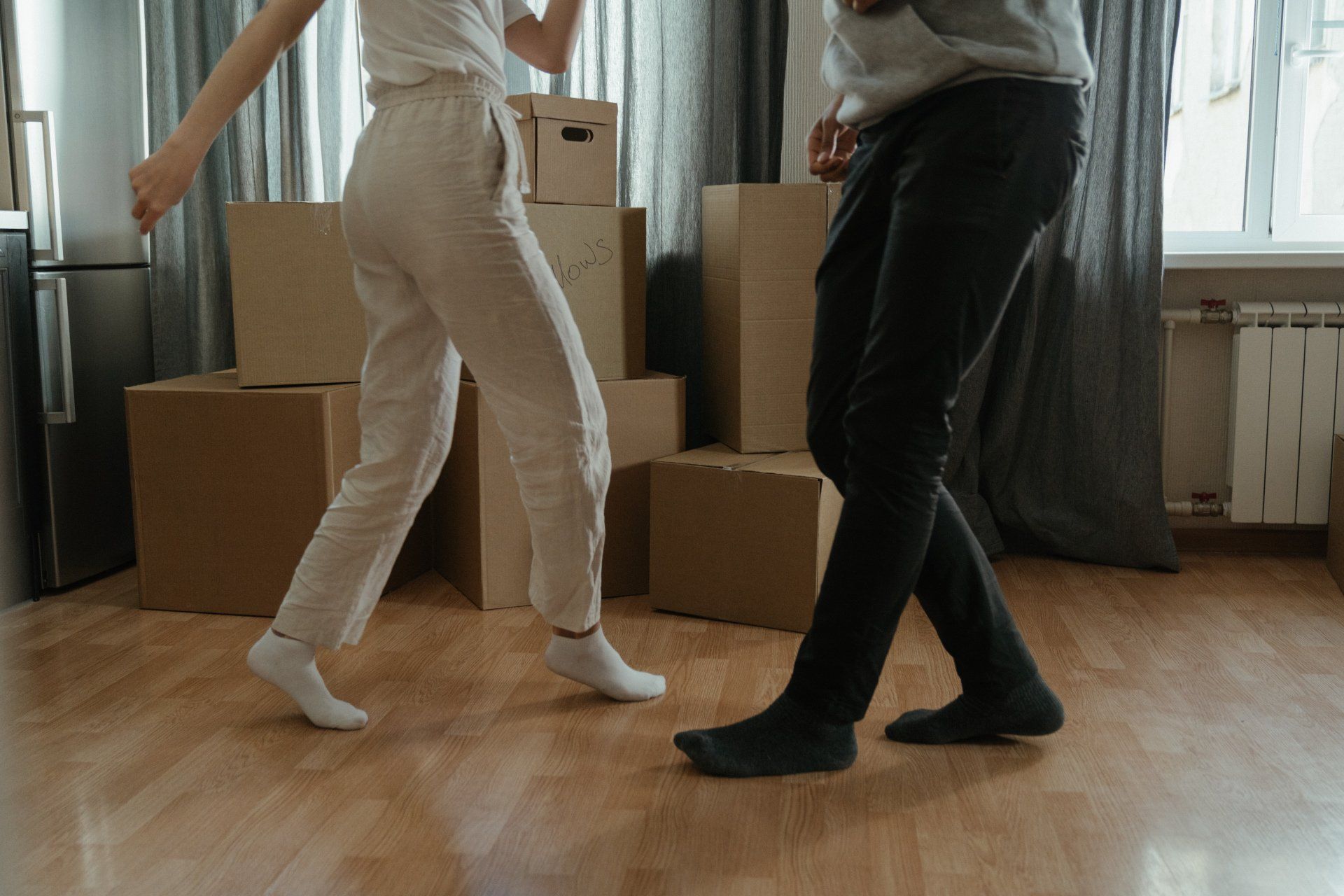 two persons walking on the floor with boxes in the background